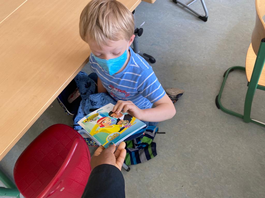 A child receiving a Rhapsody copy inside a classroom.